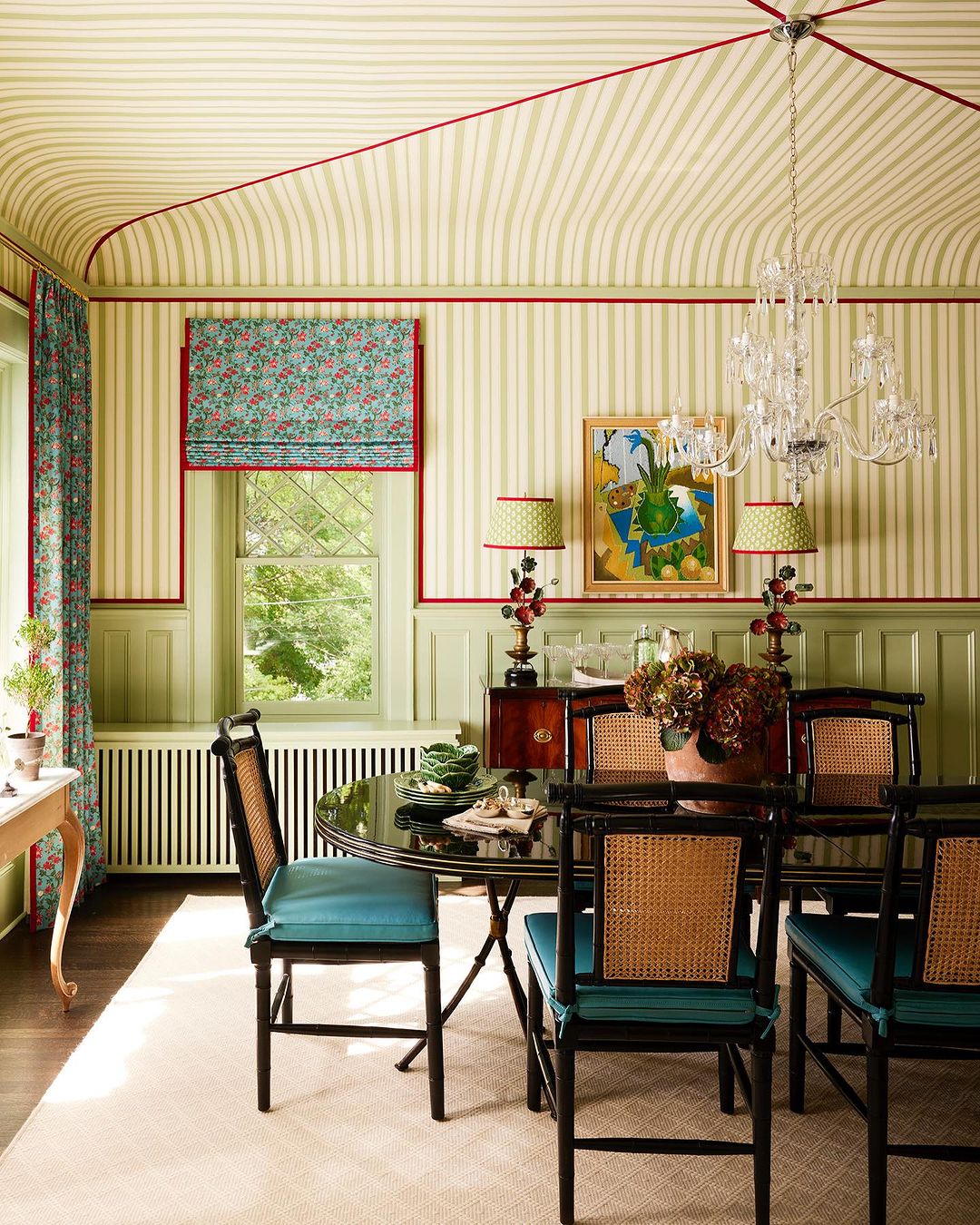 Elegant dining room with striped wallpaper, black dining set with blue cushions, crystal chandelier, and floral accents.