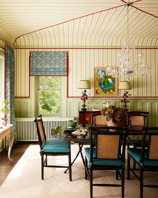 Elegant dining room with striped wallpaper, black dining set with blue cushions, crystal chandelier, and floral accents.