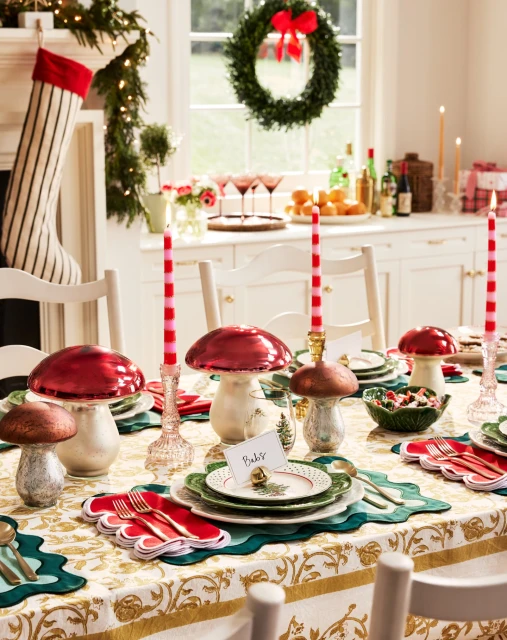 Festive holiday table setting with mushroom-shaped decor, candles, and holiday decorations in a brightly lit dining room.