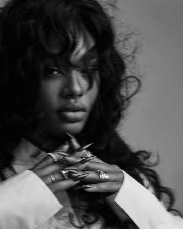 Close-up monochrome portrait of a woman with long dark wavy hair and long pointed metallic nails, photographed by David Roemer.