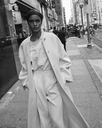Model wearing a long coat and headscarf walking down a city street, captured in black and white by David Roemer in Paris.