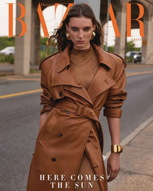 Fashion editorial shot of a woman in a brown leather trench coat on an urban street, Harper's Bazaar Greece cover.