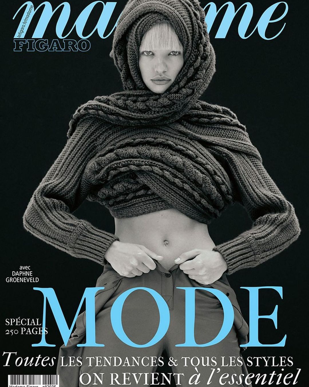 Magazine cover featuring a female model in a grey hooded knit sweater and olive pants, set against a dark grey backdrop with light blue title text.