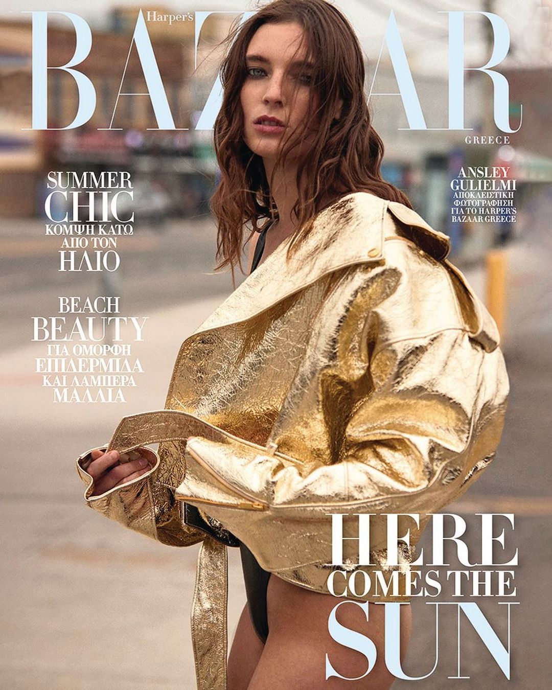 Harper's Bazaar Greece magazine cover featuring a woman in a gold jacket with the text 'Here Comes The Sun' in a blurred outdoor setting.