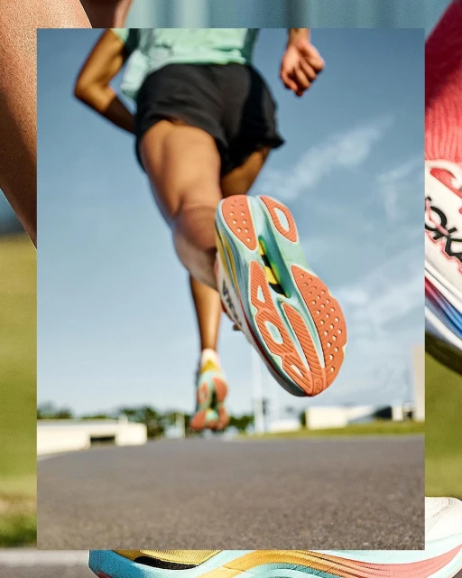 A runner is captured from a low angle, focusing on the colorful soles of their running shoes as they stride forward on a paved path.
