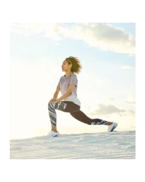 A woman in athletic wear lunging on a sandy dune against an open sky, photographed by David Salafia.
