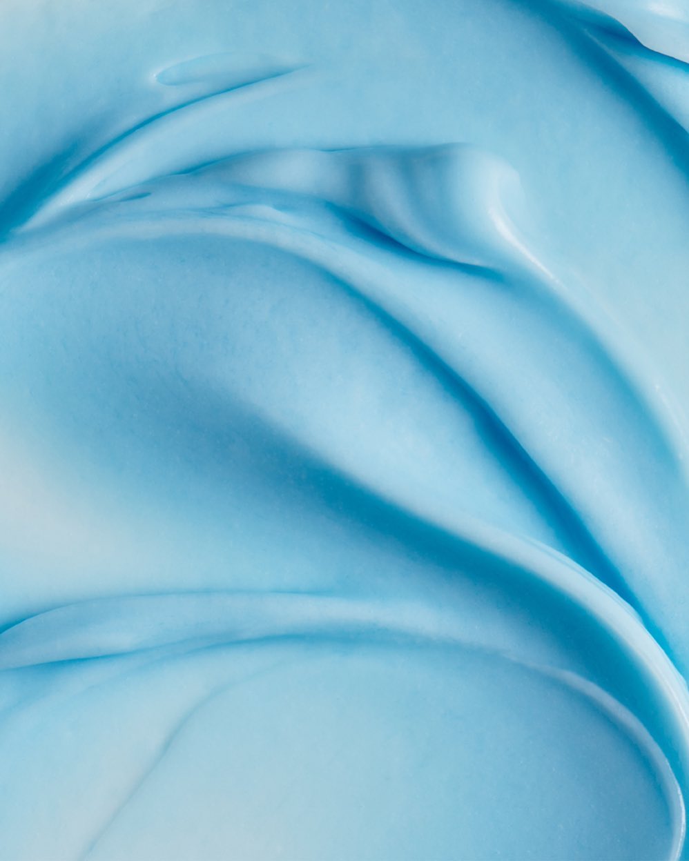 Close-up of light blue creamy texture with smooth waves, creating a visually appealing and serene backdrop for beauty or skincare products.