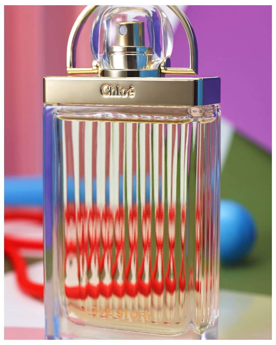 Chloe perfume bottle close-up shot featuring its transparent bottle, gold accents, and colorful geometric background.