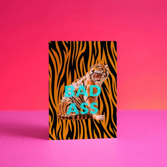 Tiger illustration with animal print on a card in a vibrant pink studio with smooth lighting and bold color contrast.