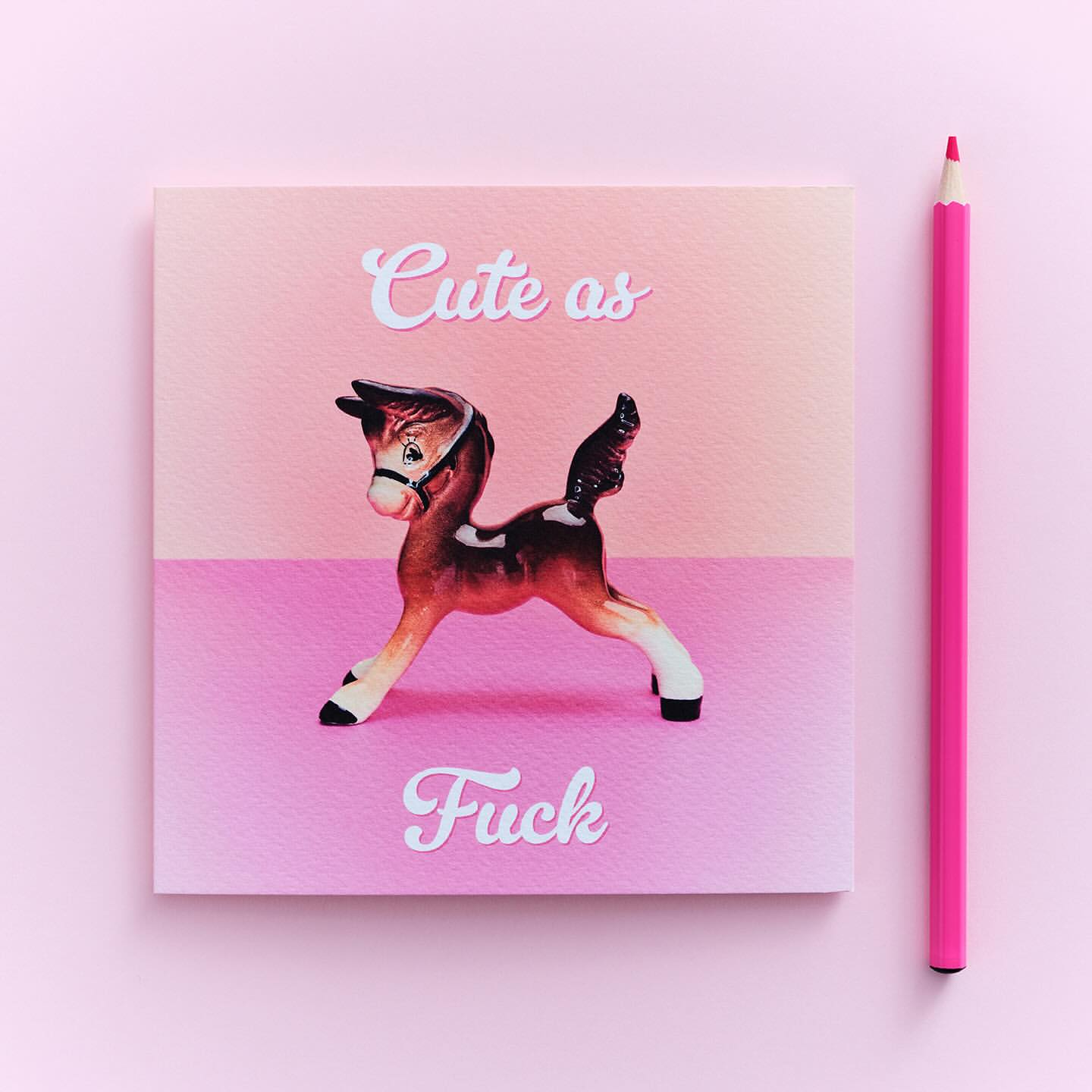 Quirky still life with a toy horse on a square card with pink hues, accompanied by a pink colored pencil.