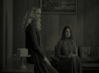 Two women indoors in a dimly lit wood paneled room photographed by David Short