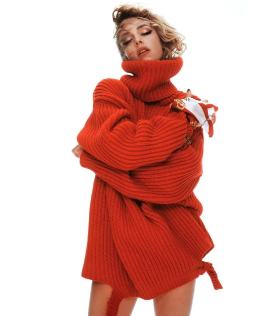 Fashion shot of a woman in a red turtleneck sweater posing against a white backdrop, studio lighting.