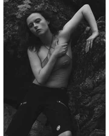 Model leaning against dark rocky terrain wearing a halter top and shorts, photographed by David Sims in New York.