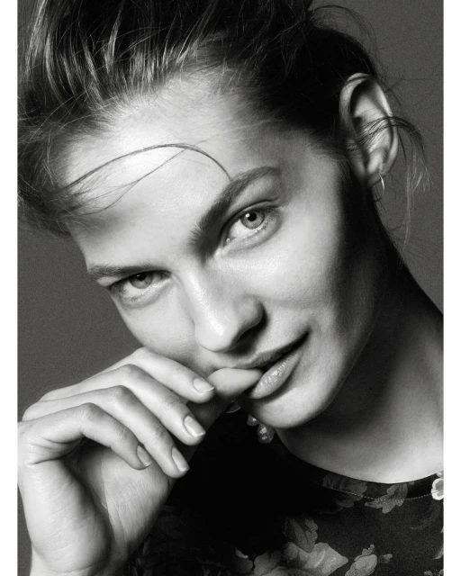 Monochrome close-up portrait of a woman with updo hairstyle, floral patterned top, and soft diffused lighting in a photo studio.
