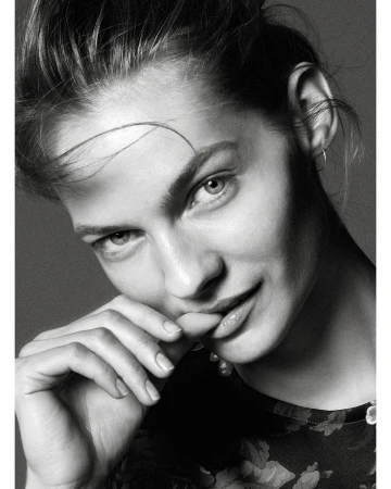 Monochrome close-up portrait of a woman with updo hairstyle, floral patterned top, and soft diffused lighting in a photo studio.
