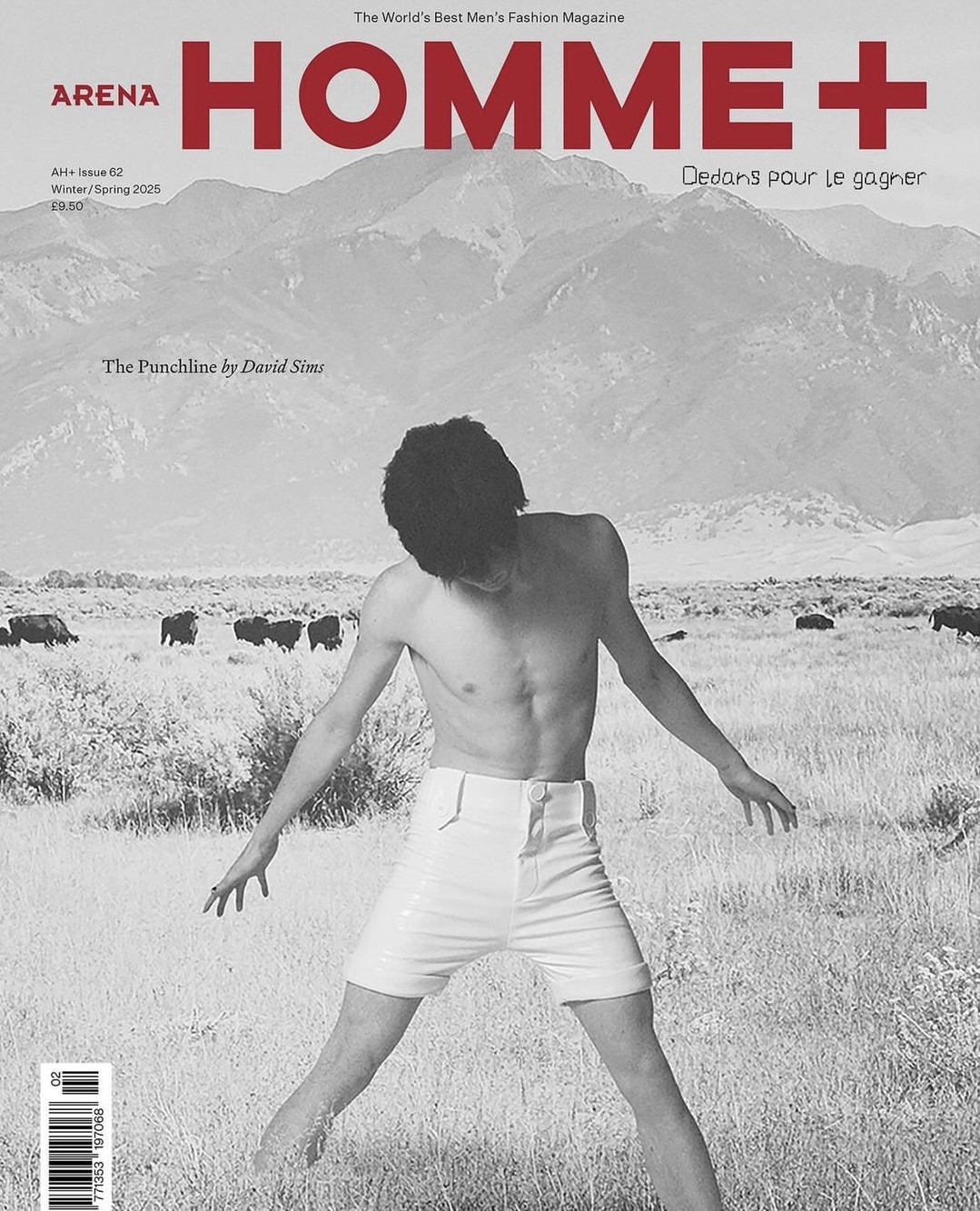 Monochrome magazine cover featuring a shirtless man in white shorts standing in a grassy field with mountains in the background