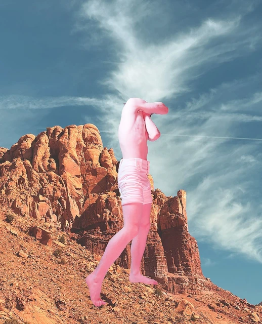Surreal art composition: Pink human figure stands on a red rock formation against a blue sky with clouds, creating a dreamlike desert scene.