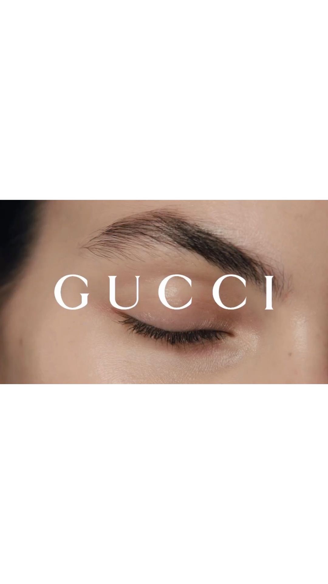 Close-up shot features a person's eye, eyebrow, and upper cheek with the word 'GUCCI' overlaid in white sans-serif font.