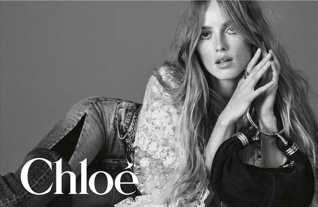 Black and white portrait of a female model lying down wearing a lace top and denim jeans, photographed by David Sims