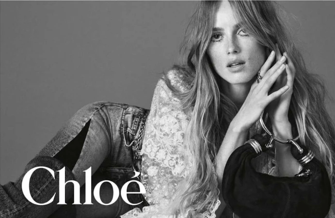 Black and white portrait of a female model lying down wearing a lace top and denim jeans, photographed by David Sims