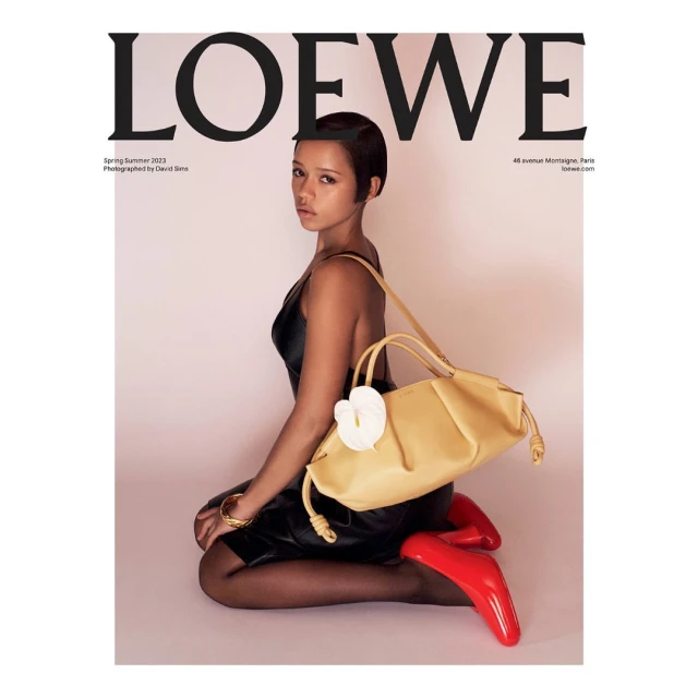 Magazine cover featuring a person sitting with a yellow purse and red shoes, shot in a studio with a light pink background.