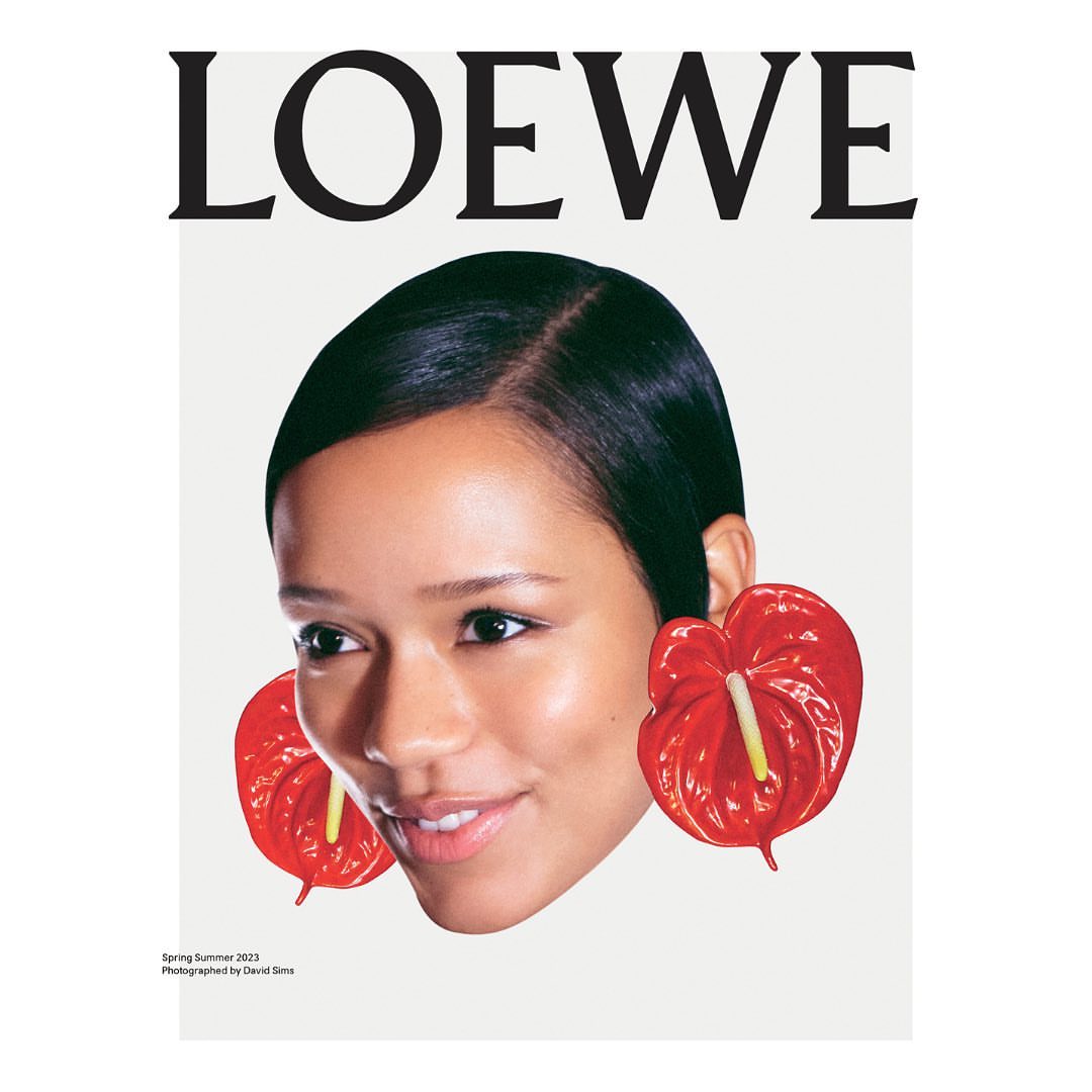 Loewe fashion brand campaign featuring a portrait of an African-American woman with red Anthurium flowers, on a white background.