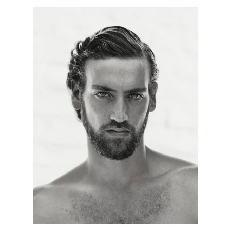 Portrait of a man with dark styled hair and a trimmed beard against a plain background