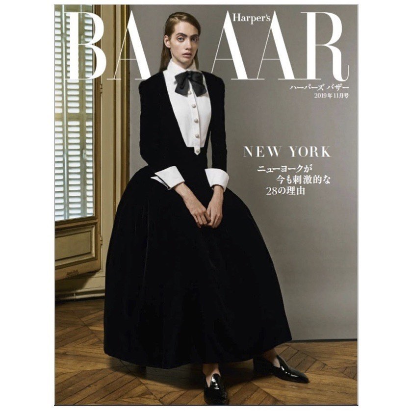 Magazine cover featuring a model in a black gown and bow tie, Harper's Bazaar. The image has window light and grey background.