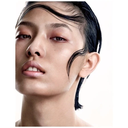 Close-up portrait of a woman with wet dark hair strands slicked across her forehead against a plain white background