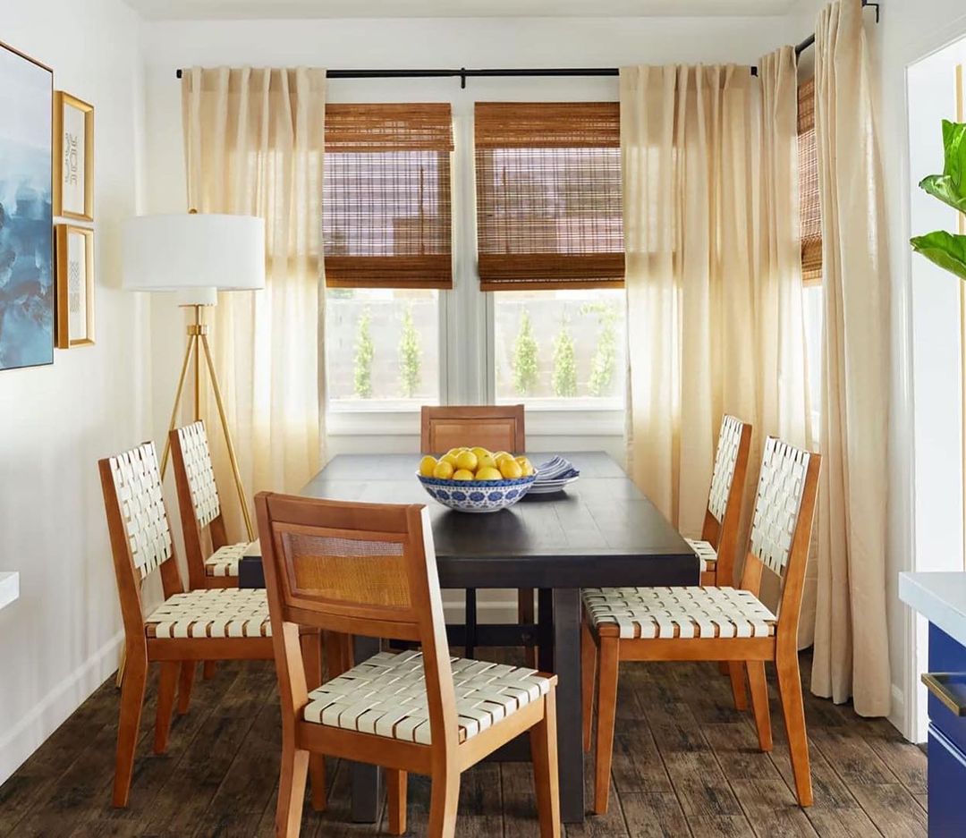 Dining room interior featuring a dark wood table with six chairs, a bowl of lemons, and natural light from window.