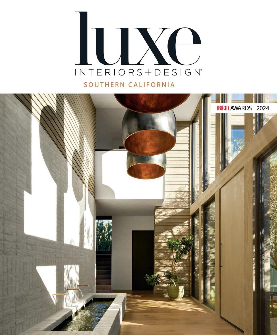 Interior design publication cover featuring a modern home interior with a water feature, pendant lights, and natural light.