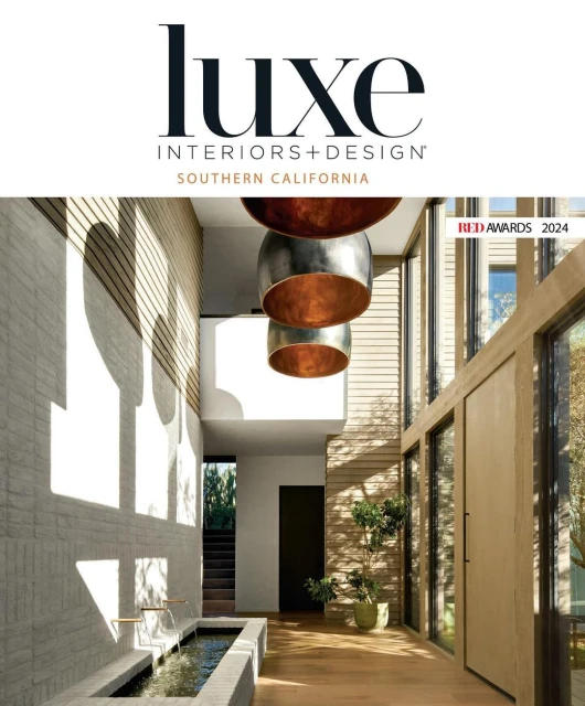Interior design publication cover featuring a modern home interior with a water feature, pendant lights, and natural light.