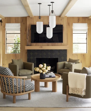 Cozy living room features four armchairs, a round coffee table, modern pendant lighting, and a fireplace with a wall-mounted TV.