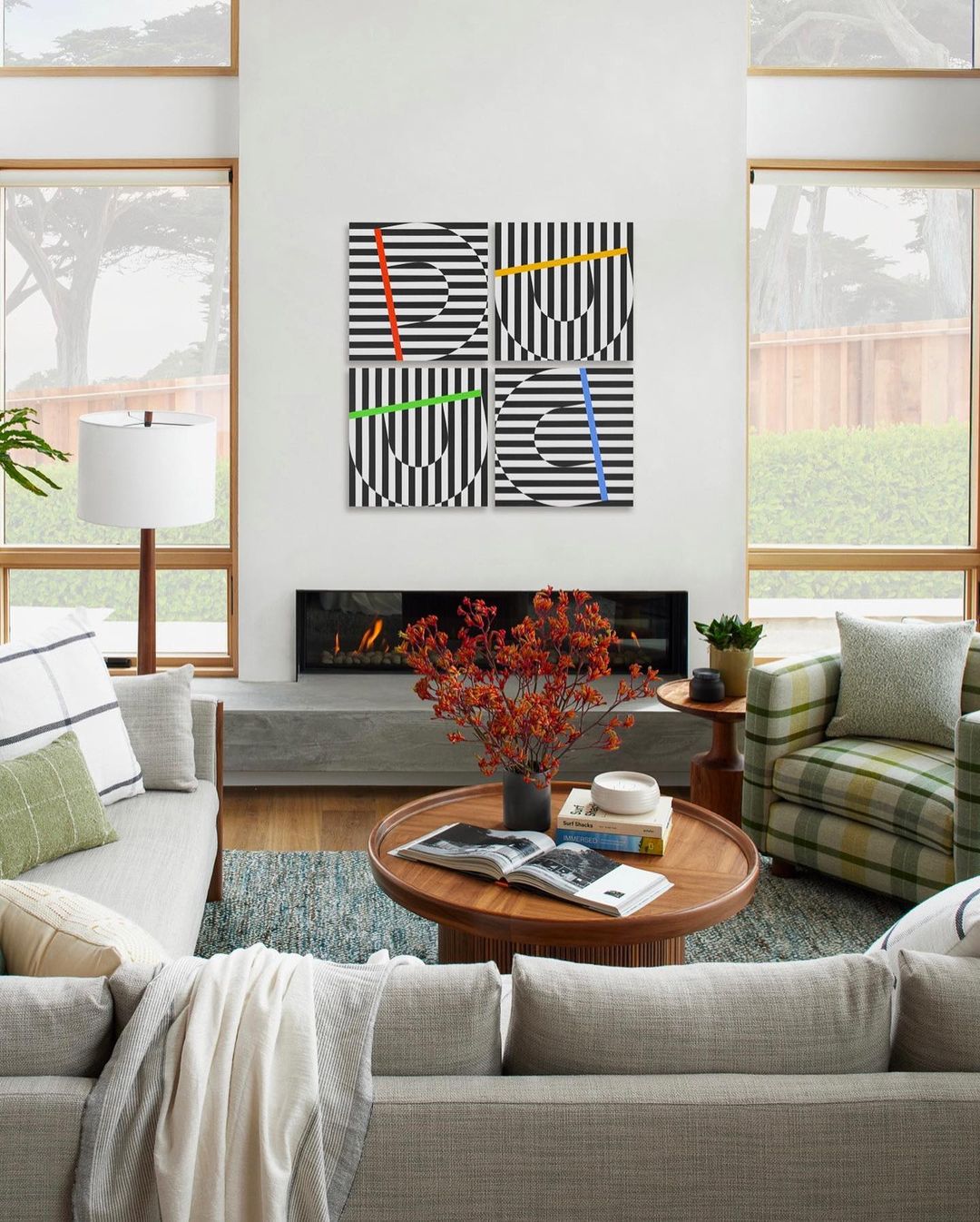 Living room featuring modern art with geometric patterns in black and white with colored vertical stripes above a fireplace.