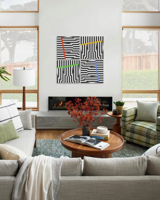 Living room featuring modern art with geometric patterns in black and white with colored vertical stripes above a fireplace.