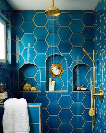 Bathroom with turquoise hexagon tiles, gold fixtures, and a white towel. A modern and colorful interior design is displayed.