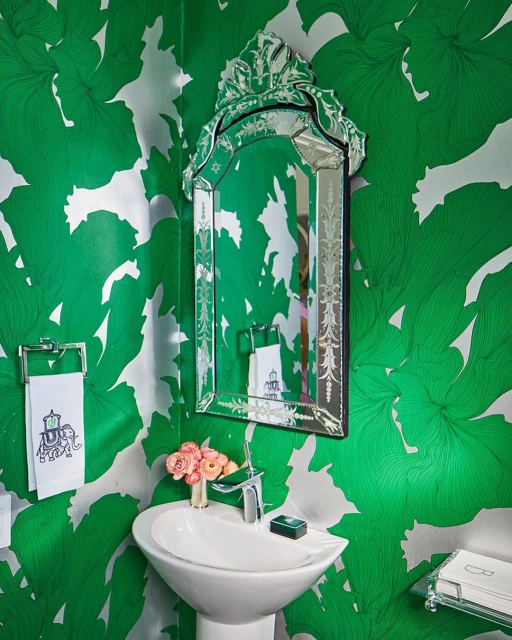 Interior bathroom featuring a white pedestal sink, ornate mirror, floral wallpaper, and decorative accents creating a stylish and vibrant space.