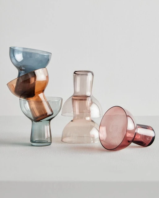 Still life of colored glasses stacked and grouped together on a white surface creating an abstract product shot in a neutral setting.