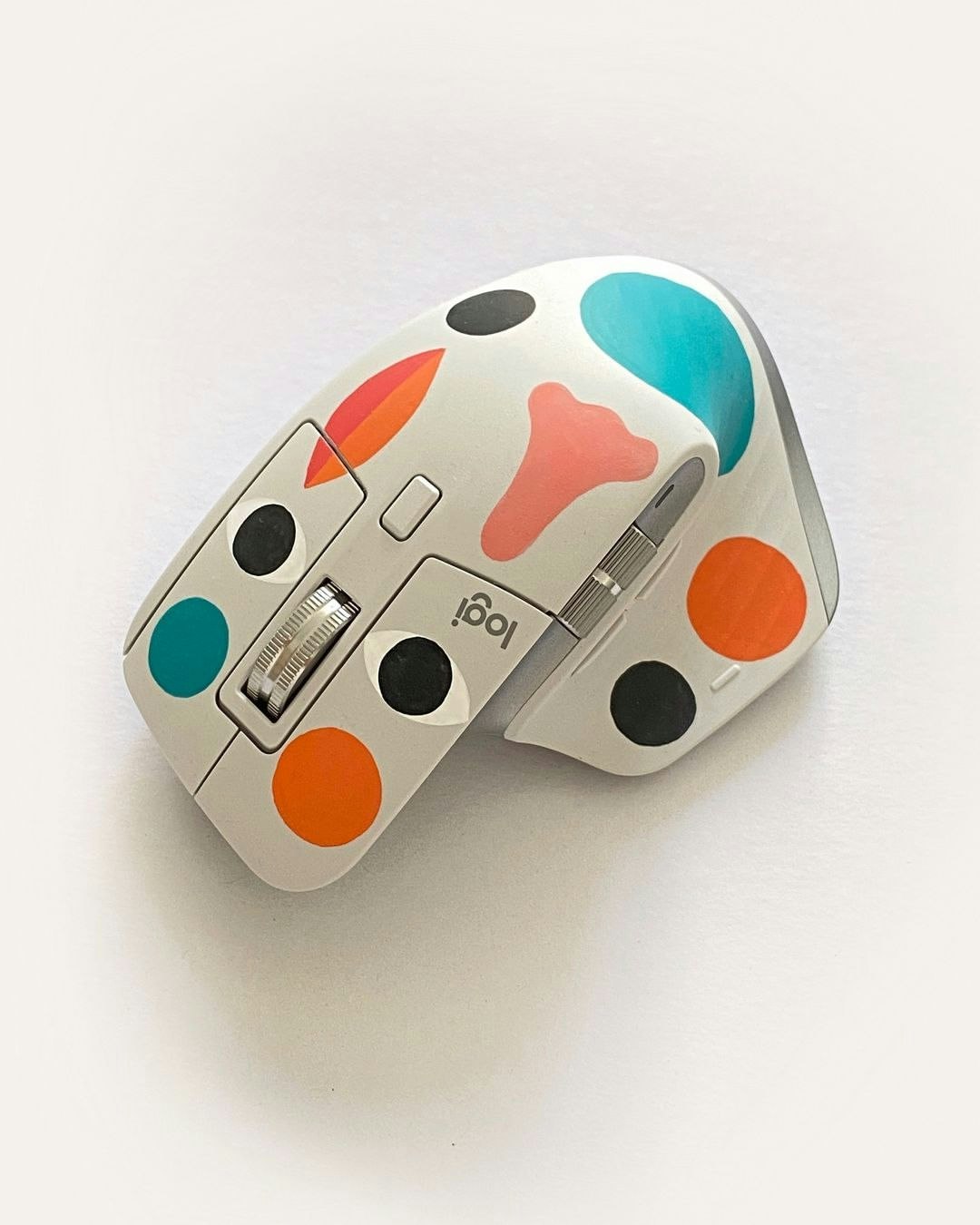 Close-up shot of a computer mouse with custom colorful polka-dot skin in an off-white color, displayed against a white background.