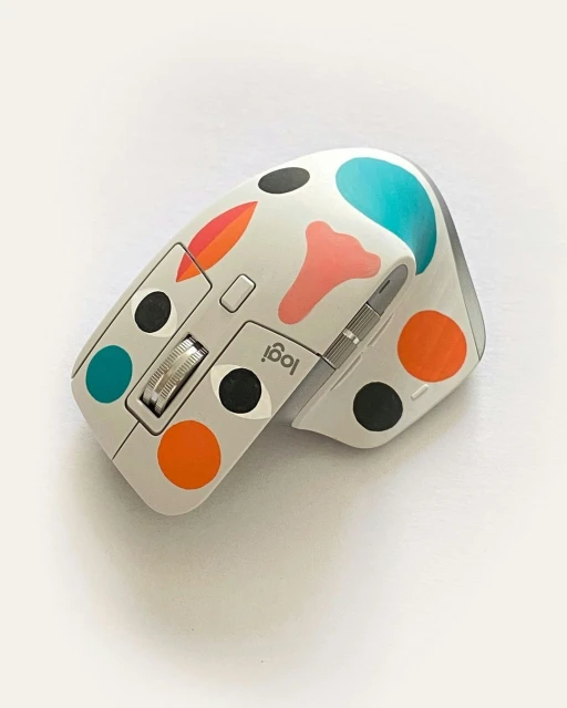 Close-up shot of a computer mouse with custom colorful polka-dot skin in an off-white color, displayed against a white background.