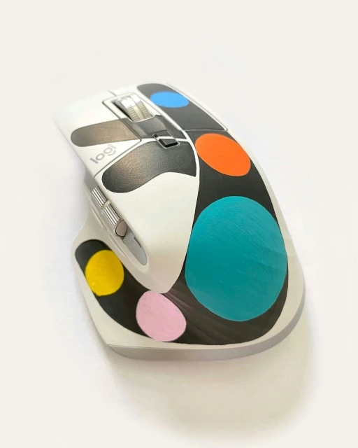 Computer mouse with a white base and colorful polka dot pattern in a studio setting on a white background, close-up shot.