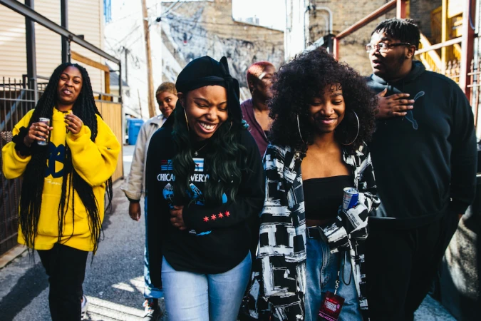 Group of African-American women and men walk outdoors in casual fashion, captured in a medium shot on an overcast day.