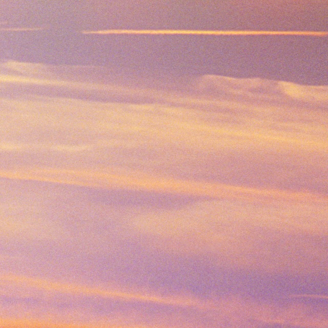 Sky with clouds in pink and yellow hues during daylight with light trails. Nature photography showcasing atmospheric conditions.