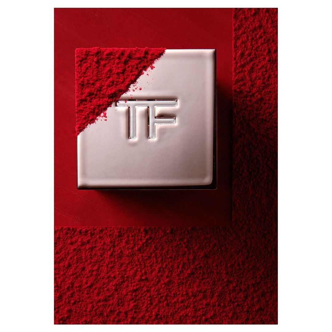 Silver cosmetic compact on a red surface partially covered with red powder, product photography, beauty and cosmetics industry.
