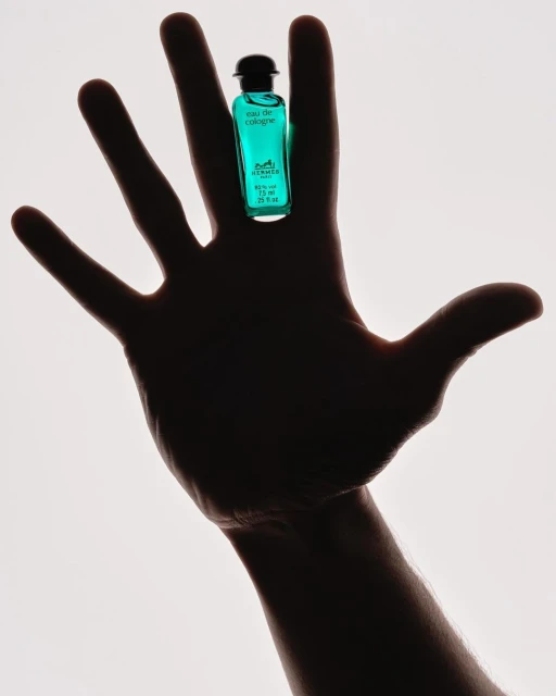 Cologne bottle held on outstretched hand against a white background in a studio shot showcasing product and human element.