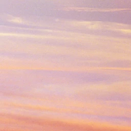 Soft pink and golden sunset sky with horizontal cloud layers stretching across the frame captured in Paris