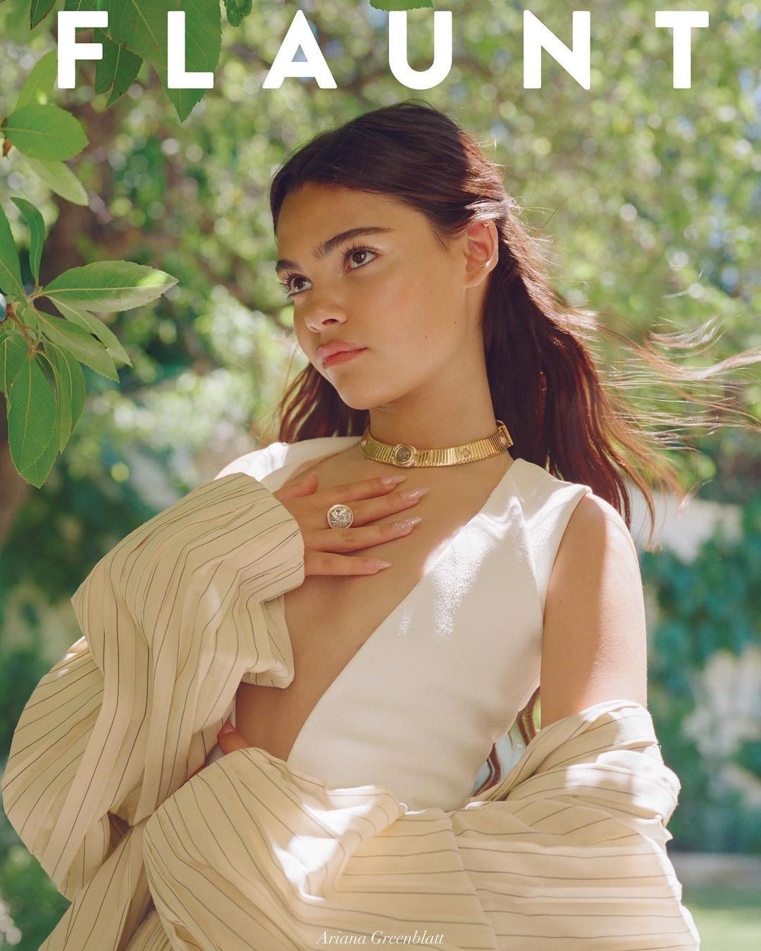 Magazine cover featuring a young woman in a white dress and gold jewelry, set against a lush green outdoor background.