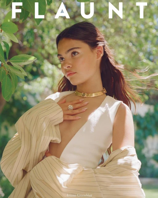 Magazine cover featuring a young woman in a white dress and gold jewelry, set against a lush green outdoor background.
