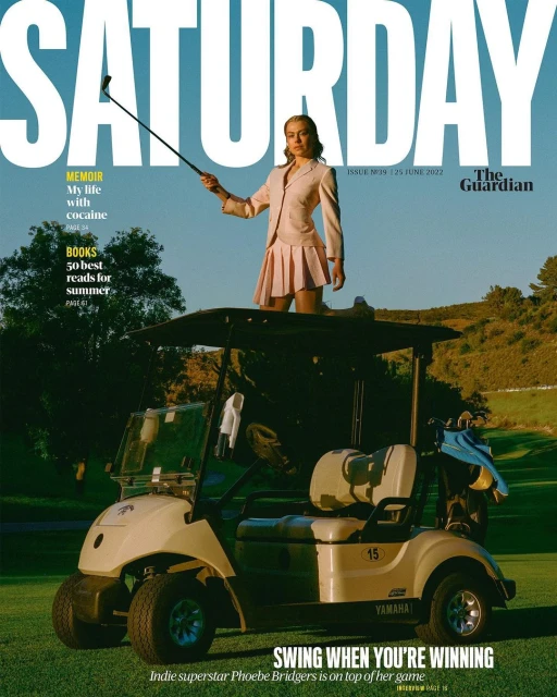 Phoebe Bridgers on a magazine cover, standing on a golf cart in a pink suit and skirt with a golf club on a sunny green golf course.