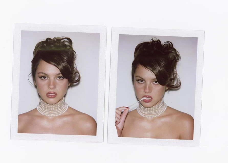 Two images of a woman with brown hair in an updo and a pearl choker. One image shows her with a white stick in her mouth.